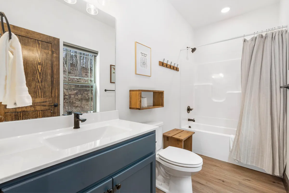 A serene bathroom featuring a spacious vanity with sink, large mirror, a calming bathtub, and warm wooden accents. The space is designed for relaxation and self-care, evoking the feel of a personal spa retreat.