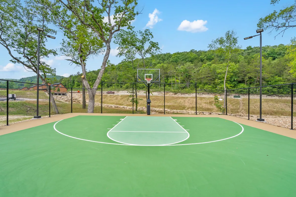 An exterior view of the basketball court set against a backdrop of surrounding trees and rolling hills. The court is vibrant and ready for energetic play, with a mountain backdrop that emphasizes its scenic, outdoor setting.